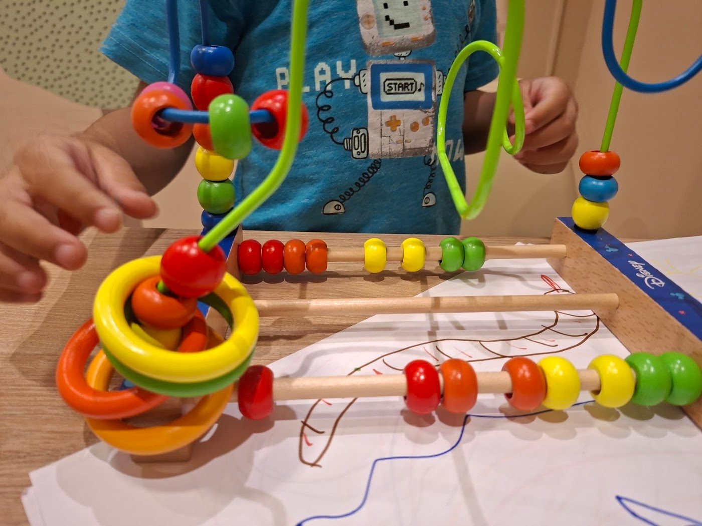 Criança brincando com aramado de contas coloridas